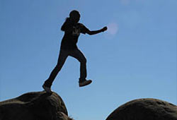 Girl leaping among rocks